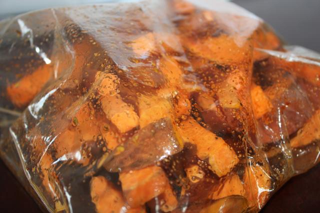 Sliced sweet potatoes marinading in a bag