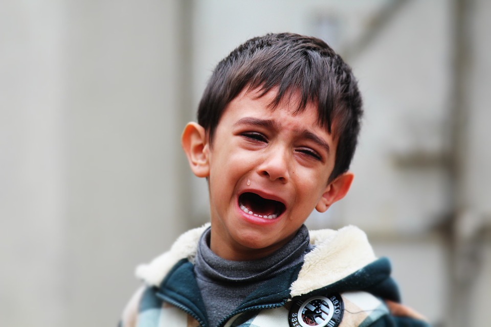 child crying because of painful mouth ulcers