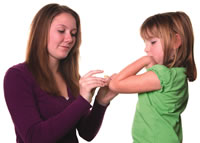 woman checking a child's elbow for a cut