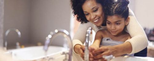 Mother helping daughter wash her hands