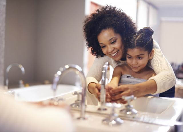 Mother helping daughter wash her hands