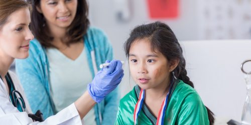 Female emergency room doctor uses a pen light to examine a young soccer player's eyes