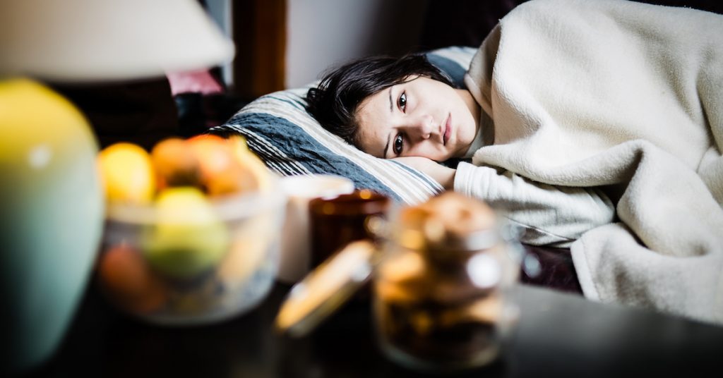 sick woman laying in bed