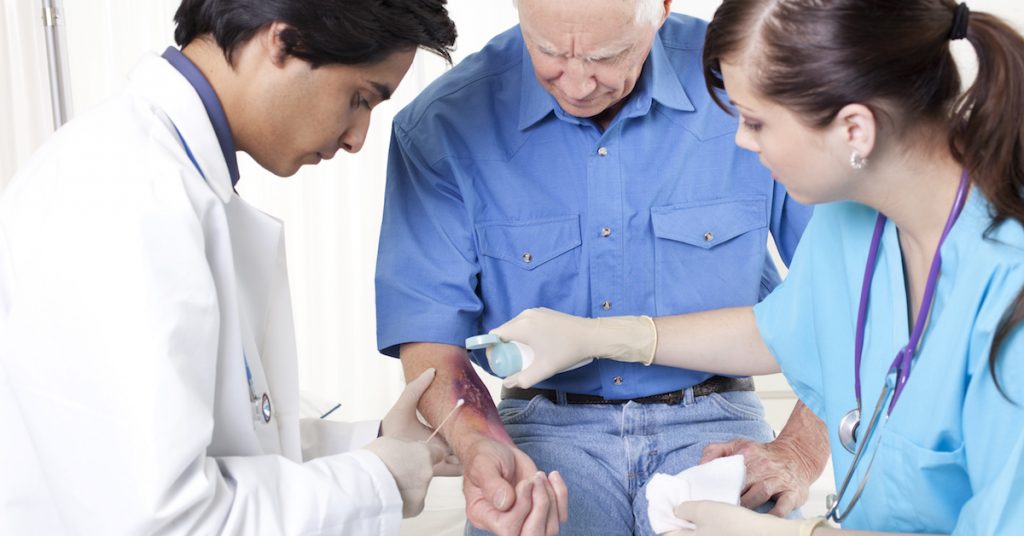 Picture of a doctor and nurse looking at a burn wound.