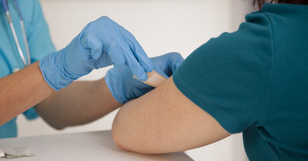 Picture of a nurse at a pharmacy clinic giving a flu shot to a patient.