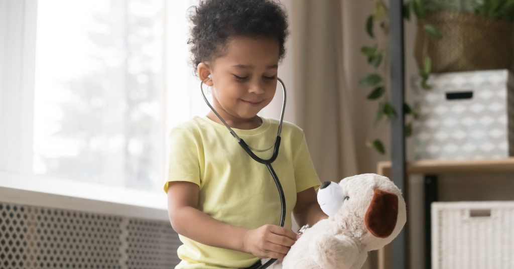 Image of little boy checking his teddy bear's heart