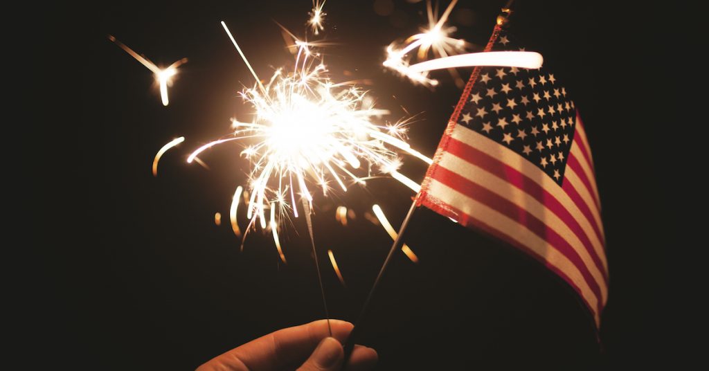 picture of Hand holding lit sparkler with American Flag