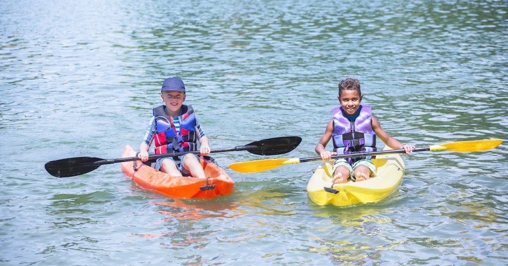 Two Kids in kayaks on a lake